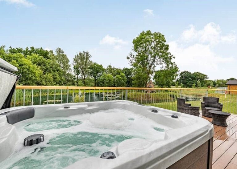 Hot tub on the veranda of a log cabin at Flaxton Meadows
